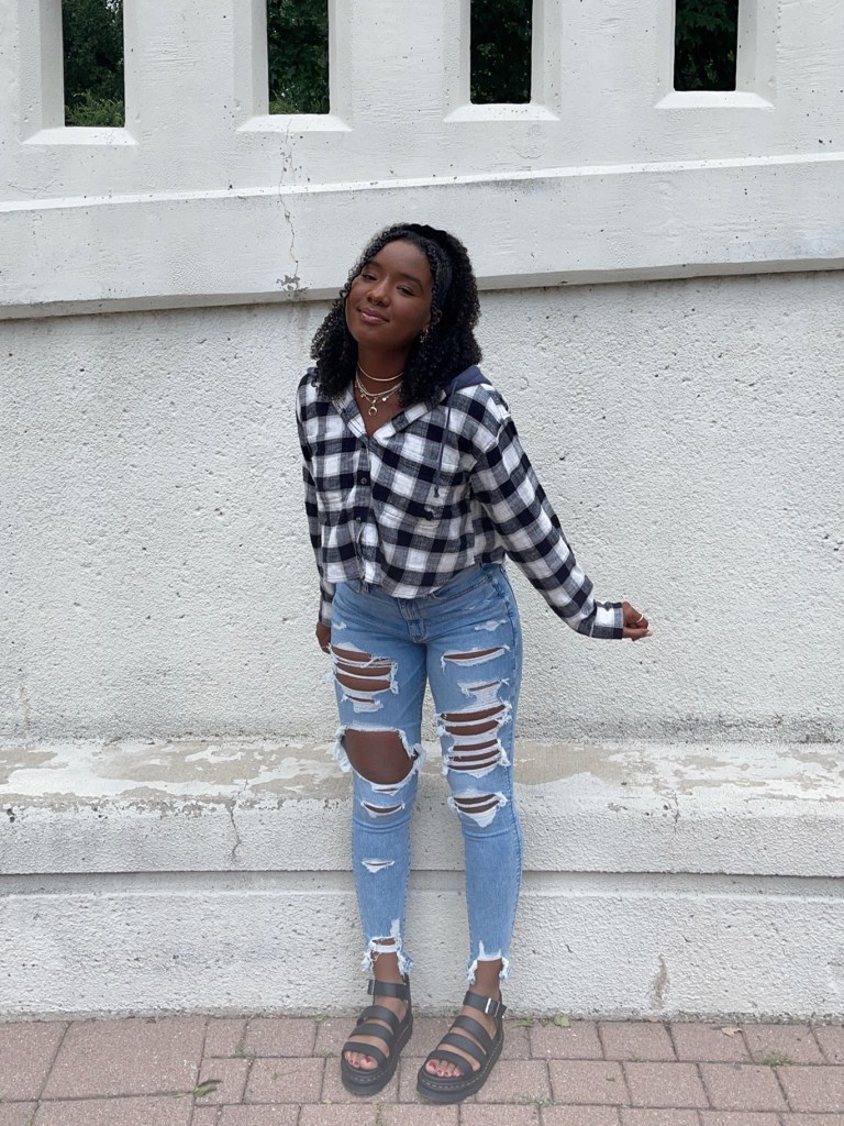 woman wearing a black and white flannel and light wash ripped jeans