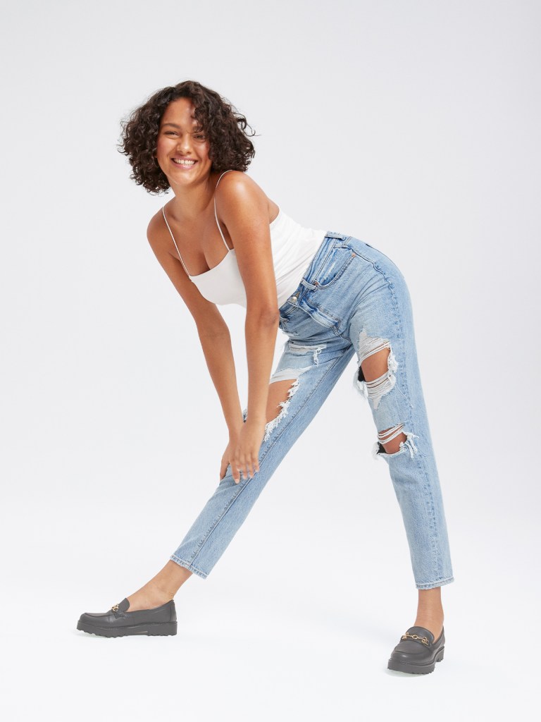 woman wearing a white tank top and ripped mom jeans in a light wash