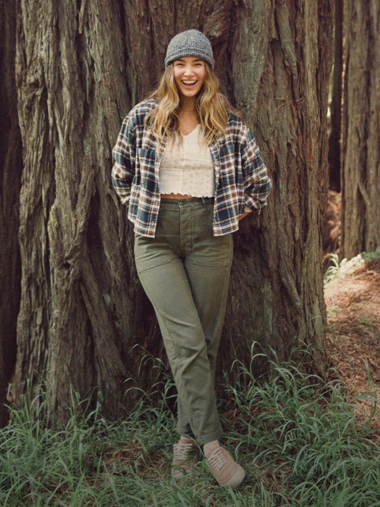 girl wearing green jeans, a flannel shirt, and a gray beanie hat
