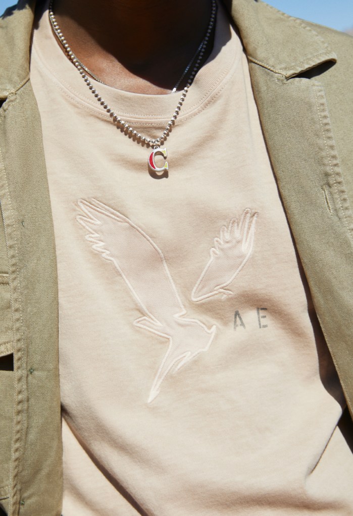 close up image of a guy wearing a beige tshirt and green jacket