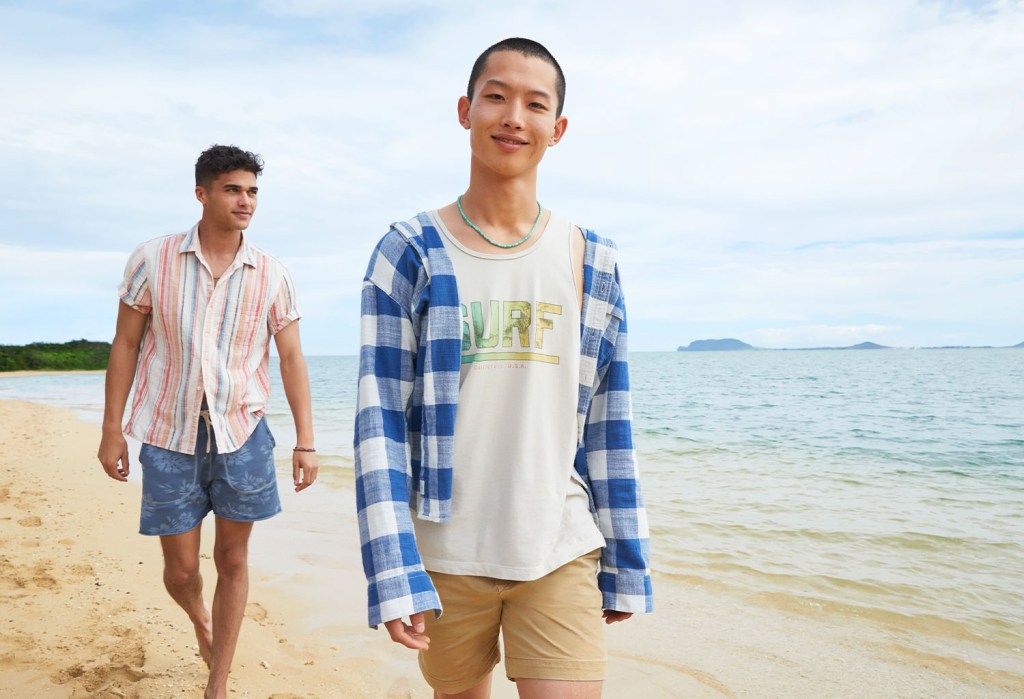 two guys wearing American Eagle shorts and tshirts walking on a beach