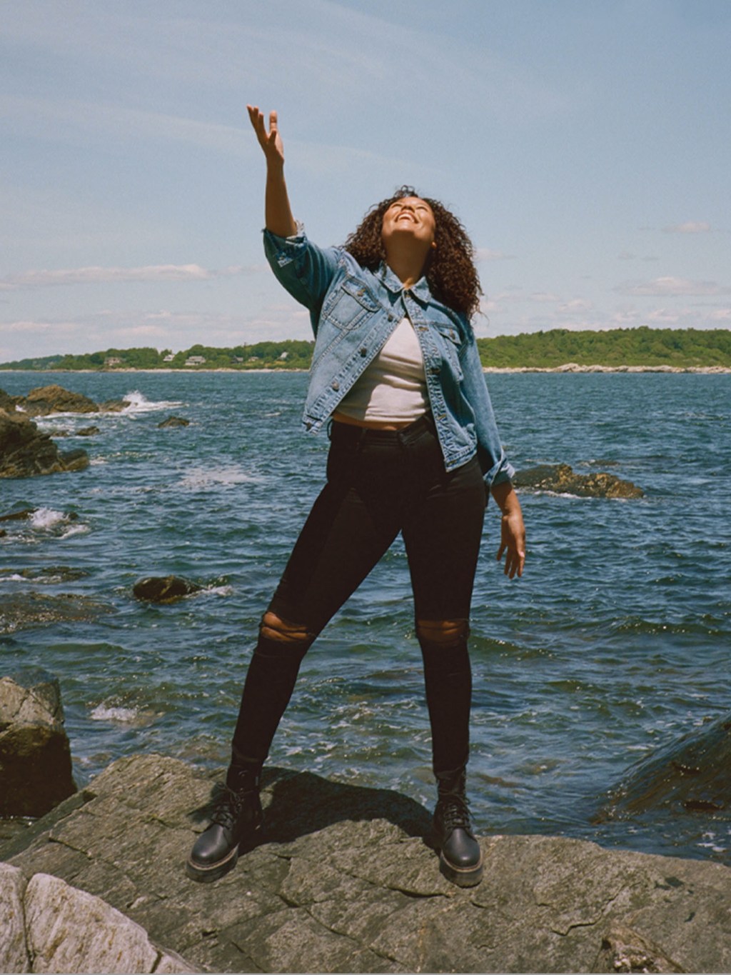 woman wearing american eagle jeggings and denim jacket in front of an ocean background