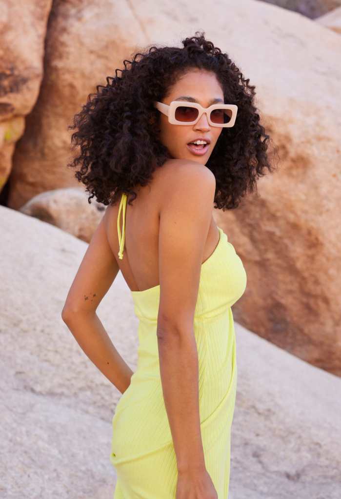 girl wearing a yellow dress from American Eagle standing in front of a rocky outdoor background