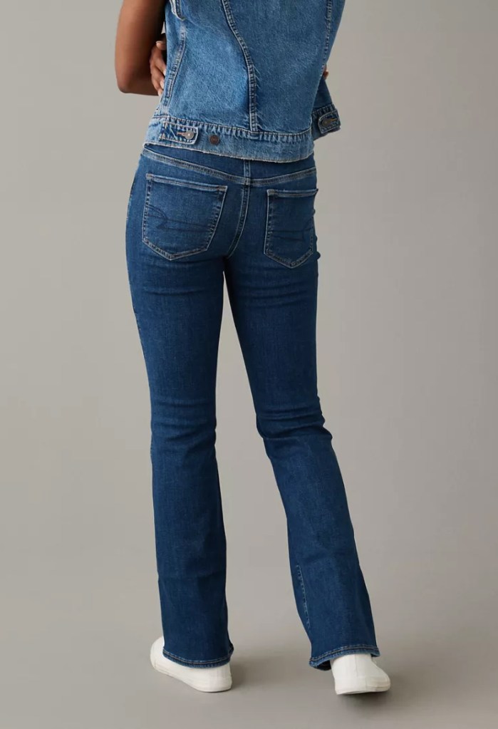 girl wearing a denim vest and medium wash bootcut jeans from American Eagle