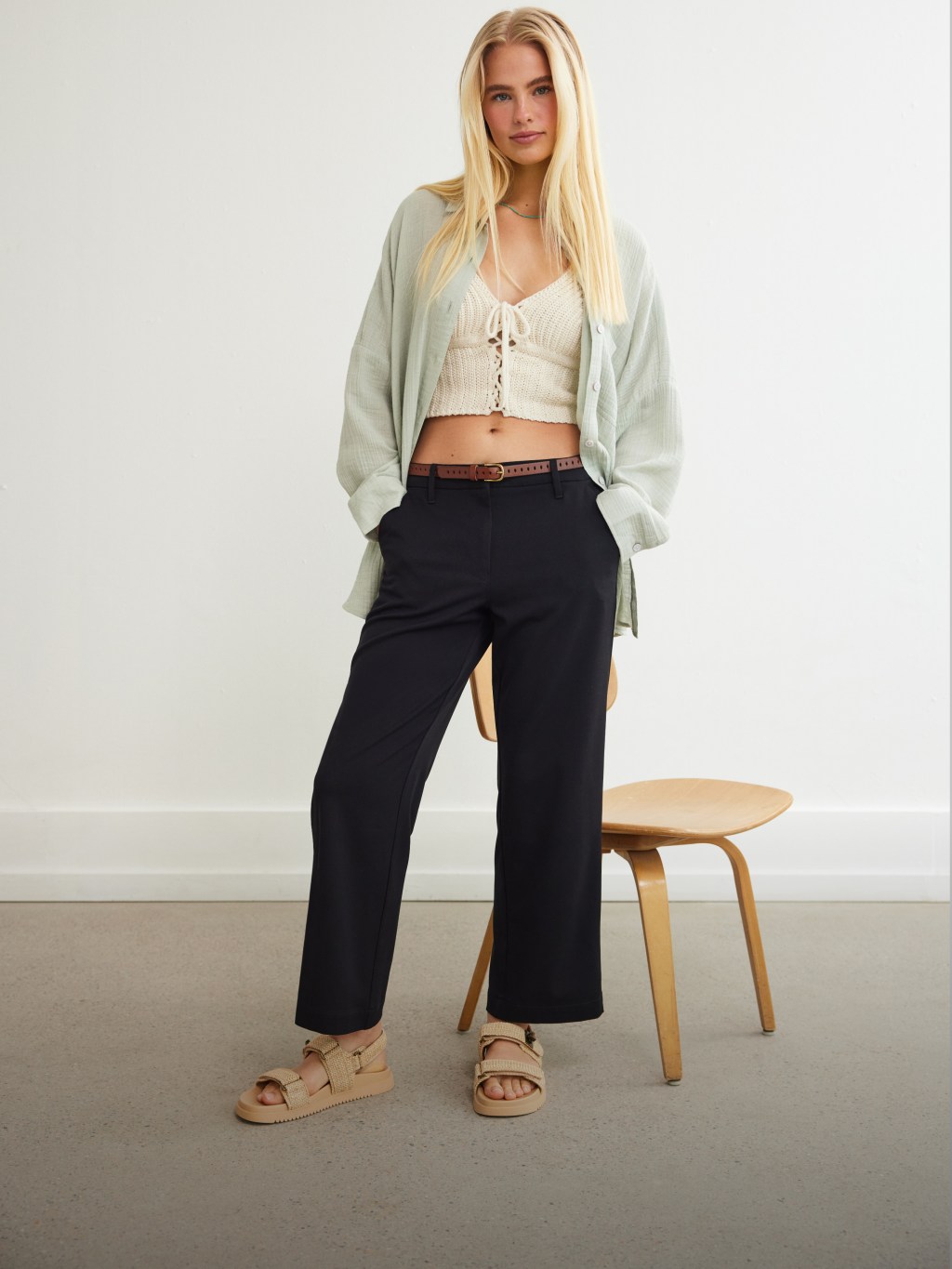 girl with blonde hair wearing a white crop top and black trousers from American Eagle