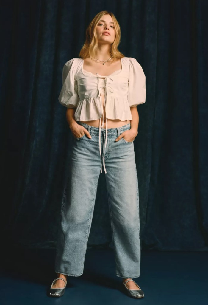 girl wearing a pretty white blouse and light wash barrel jeans from american eagle