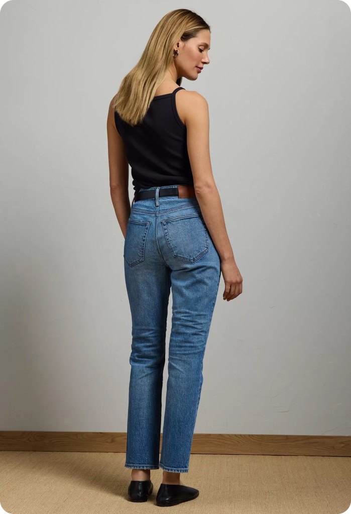 woman wearing medium wash cigarette jeans, a black tank top, and black flats