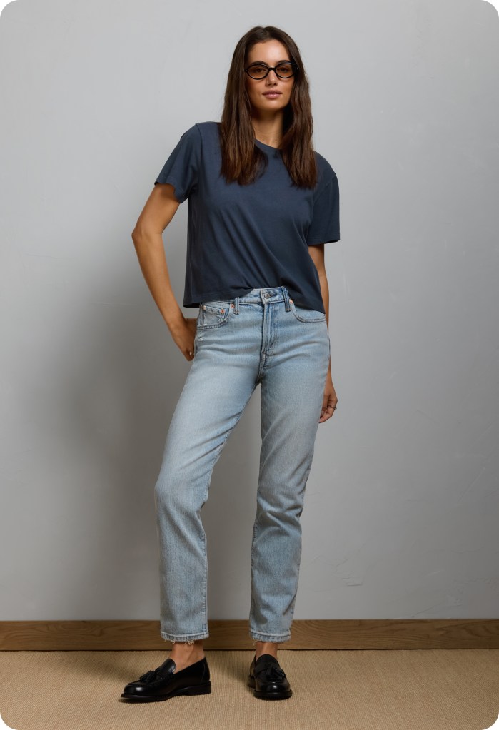woman wearing light wash cigarette jeans, a navy shirt, and black loafers