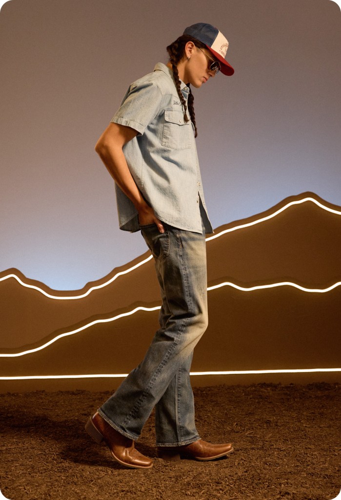 guy wearing a country concert outfit of blue bootcut jeans, denim shirt, and cowboy boots from American Eagle
